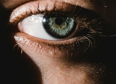 Close-up of a person's eye reflecting a calm landscape.